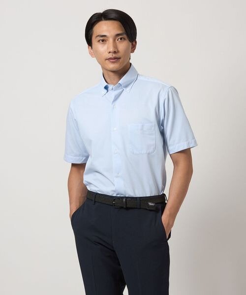 青シャツをタックインにして着ている男性