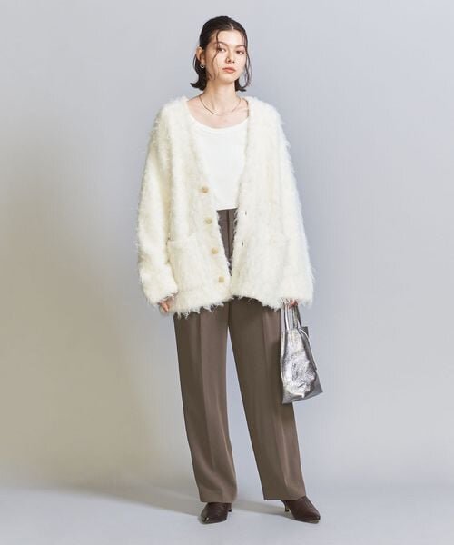 茶色のパンツ×白のカーディガンの女性