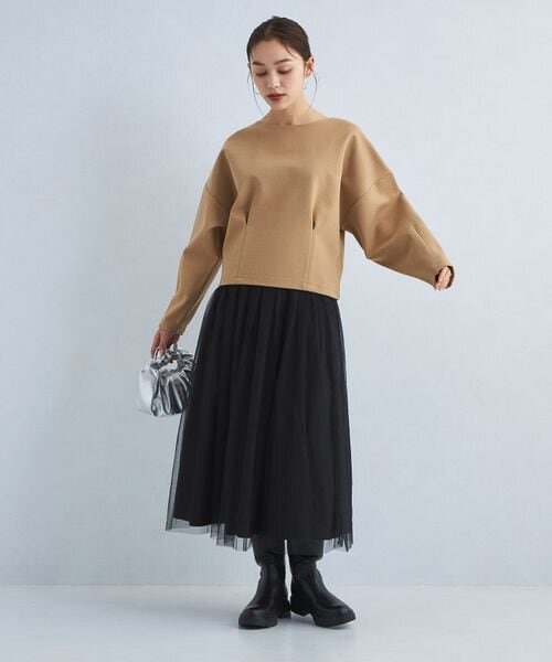 茶色のトップス×黒のスカートの女性