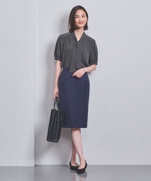 グレーのブラウス×ネイビーのスカートを着用している女性