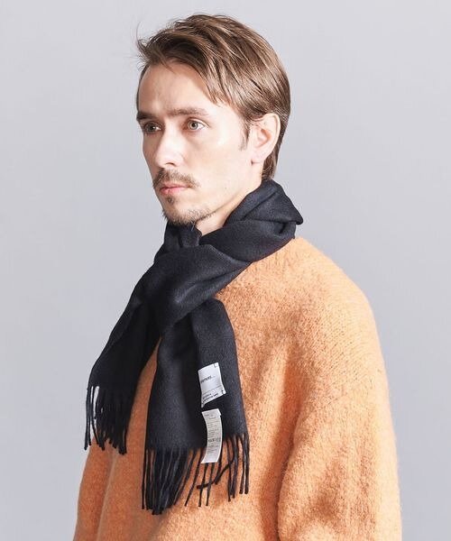 オレンジのニットに黒のマフラーをした男性