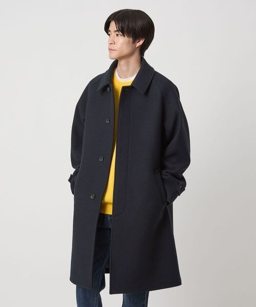 黄色のニットにステンカラーコートをあわせたコーデ