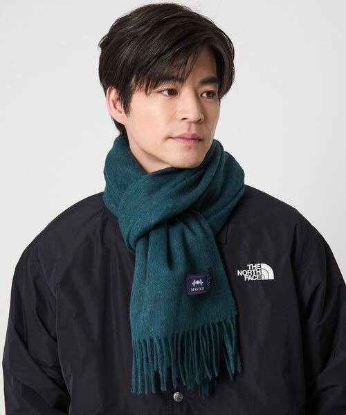 黒のアウターにターコイズのマフラーをした男性