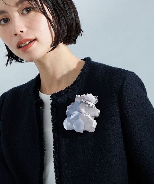 ジャケットの胸元に美しいコサージュをつけた女性