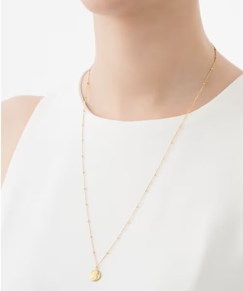 コインモチーフのネックレスをつけた女性