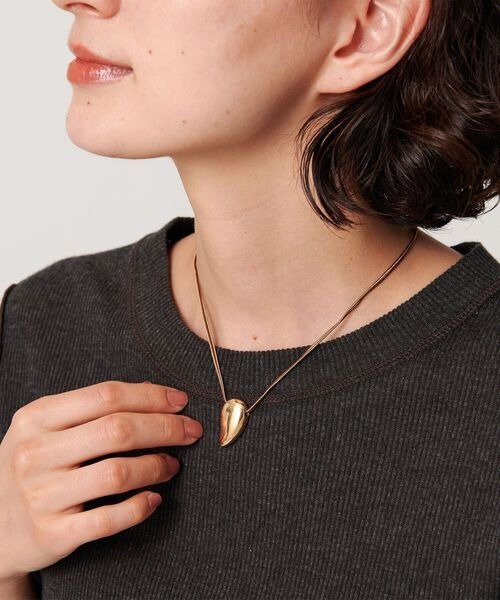 しずくモチーフのネックレスをつけた女性