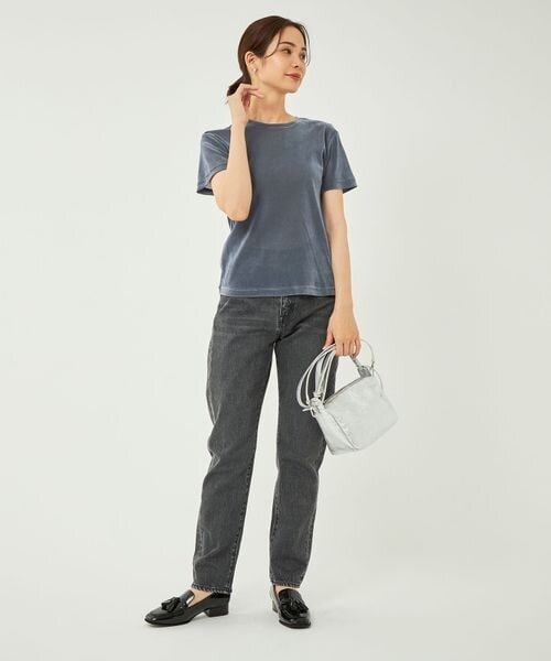ベロアのTシャツとデニムパンツを着用した女性