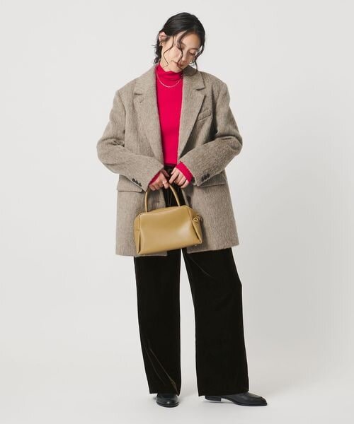 ダークブラウンのパンツにアウターをあわせた女性