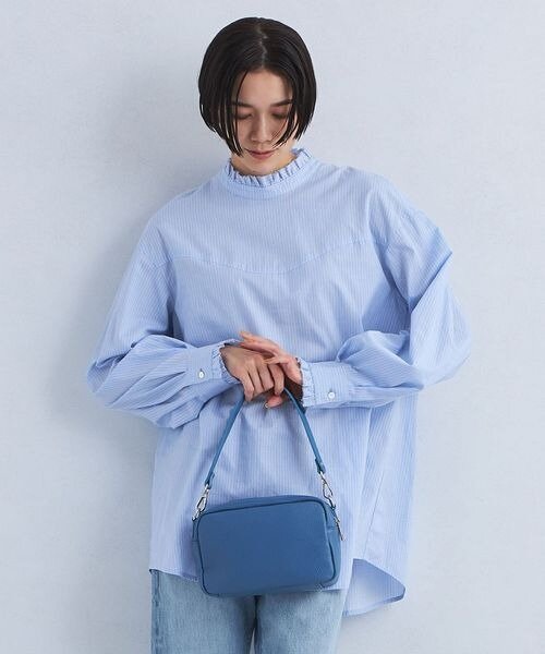 ライトブルーのフリルネックブラウスを着用している女性