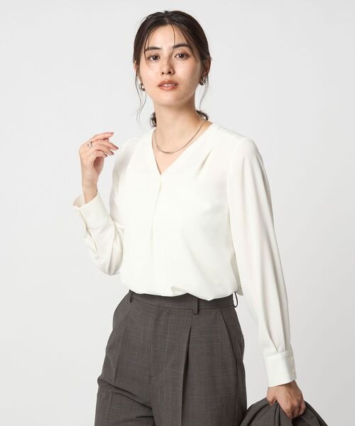 Vネックデザインの白ブラウスを着た女性