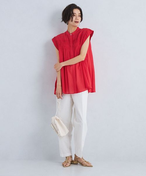 赤のブラウスに白のパンツを着用した女性