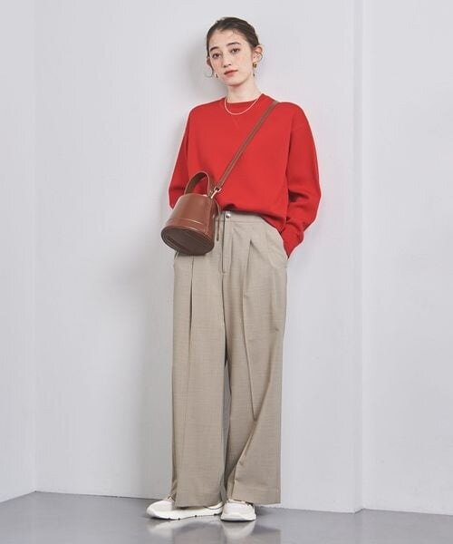 赤のニット×ベージュのパンツを着用した女性
