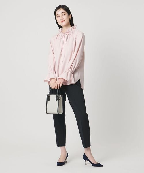 ネイビーパンツにピンクのトップスをあわせた女性