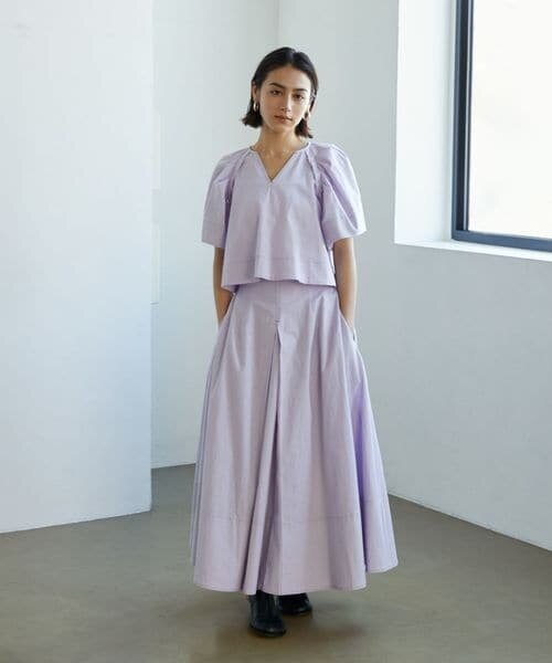 ライラックカラーのブラウスとスカートを着た女性