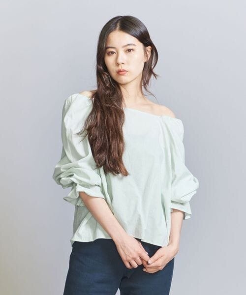 ライムカラーのギャザーブラウスを着た女性