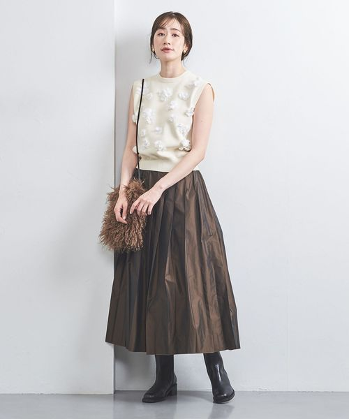 コンパクトなニットベストとフレアスカートを着た女性