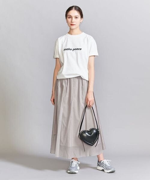 白のトップスとグレーのスカートを着た女性