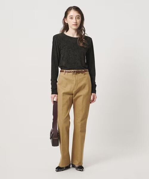 黒のトップスとベージュのパンツを着た女性
