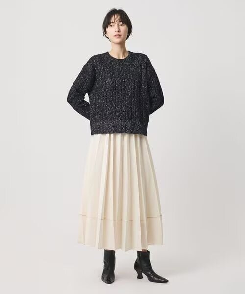 ニットとプリーツスカートのコーデの女性