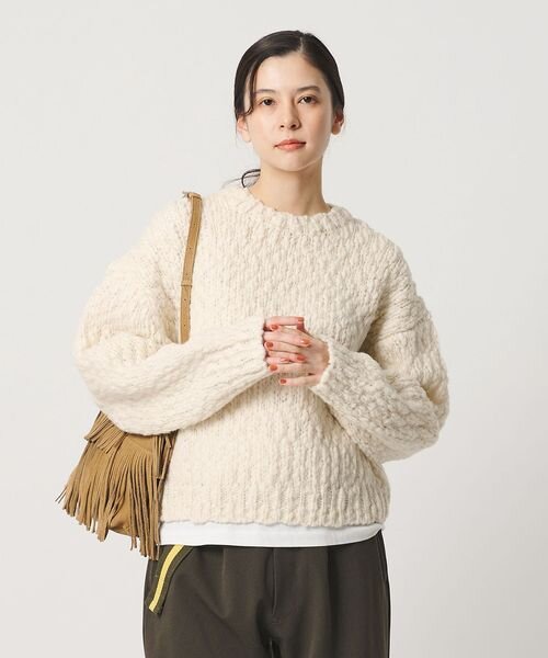 オフホワイトのニットを着た女性