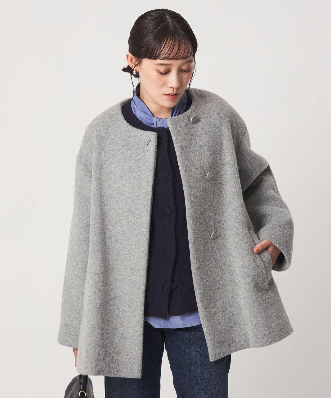 ショート丈のノーカラーコートを着た女性