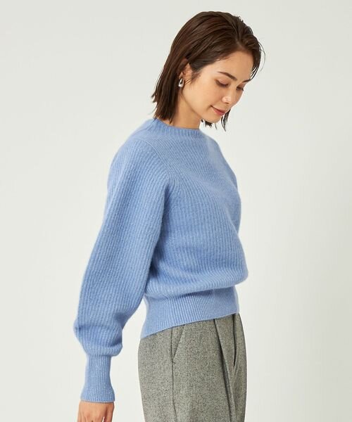 くすんだ青のニットを着た女性