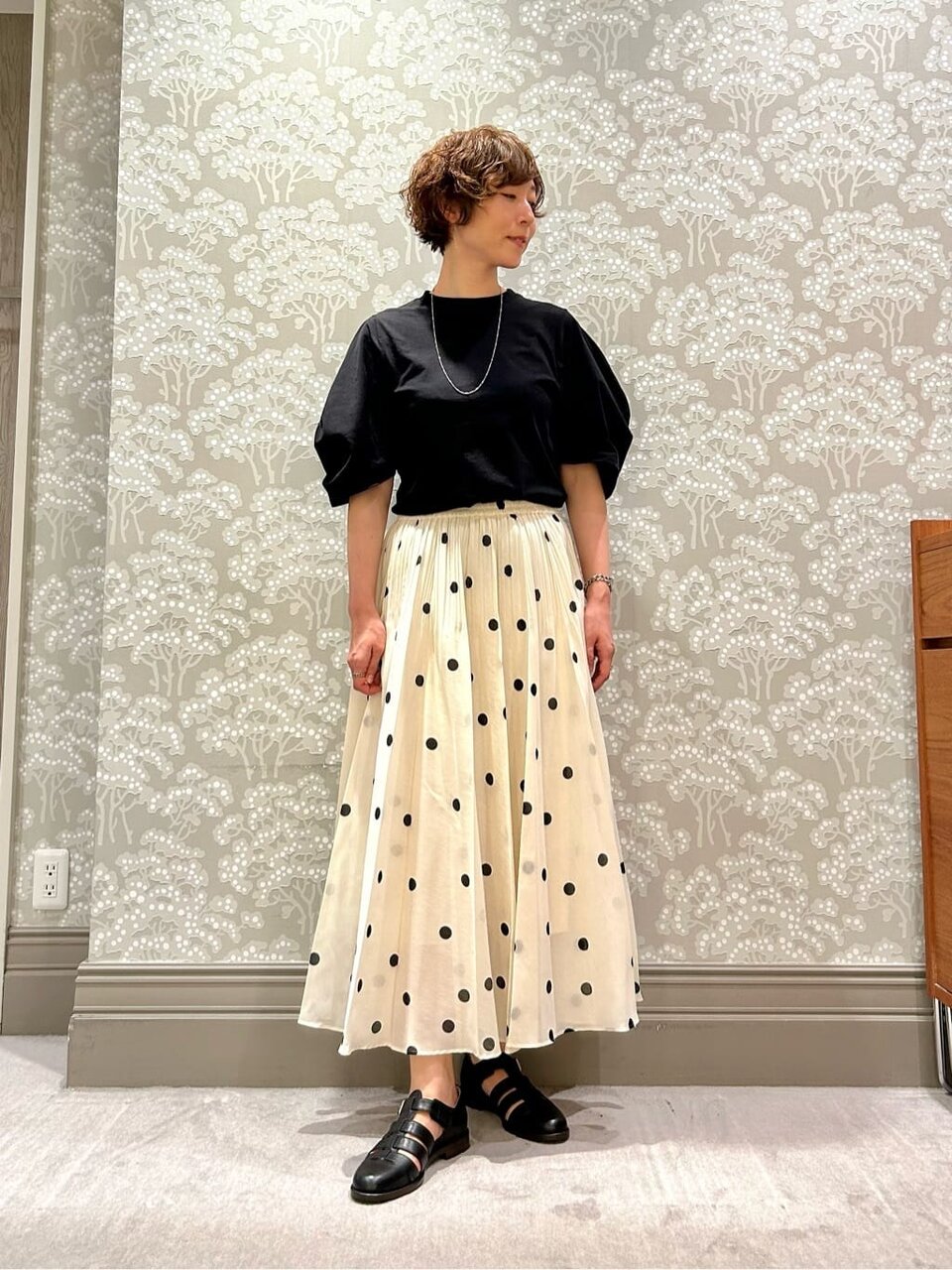 黒いTシャツにドット柄スカートを着た女性