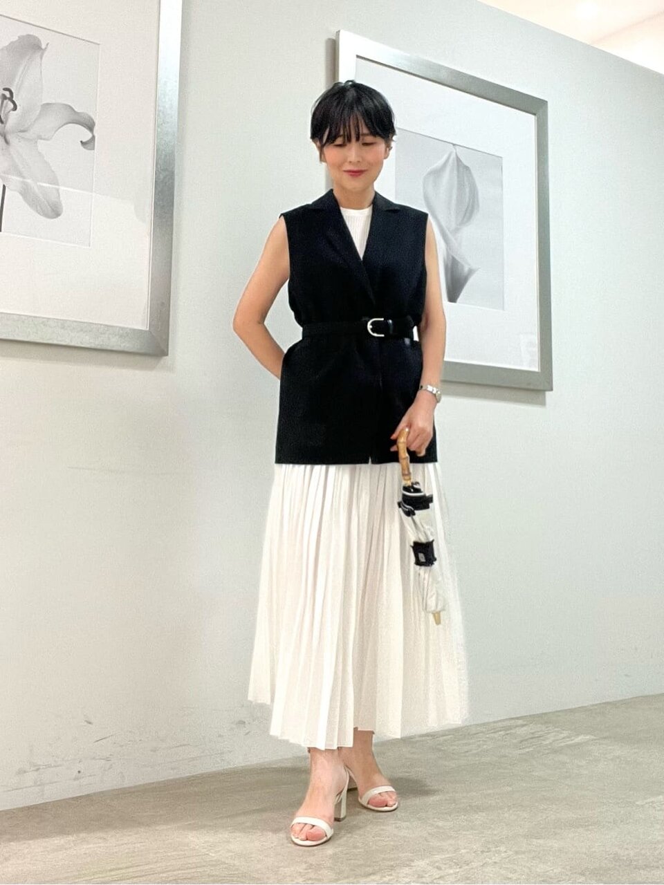 黒いジレと白いスカートを着た女性