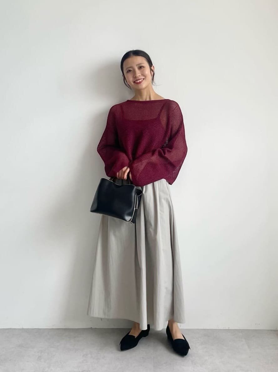 黒のトップスにチェックのプリーツスカートを着た女性