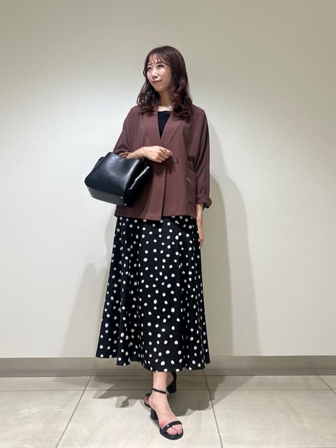 黒のトップスにチェックのプリーツスカートを着た女性