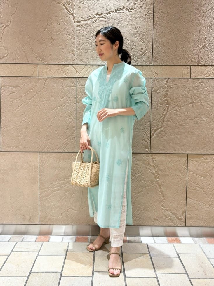 白いニットベストとグリーンのパンツを着た女性