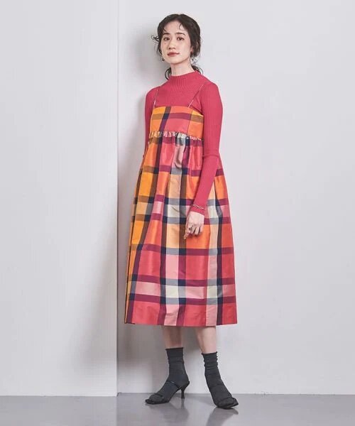 ピンクのインナーとチェック柄のキャミワンピースを着た女性