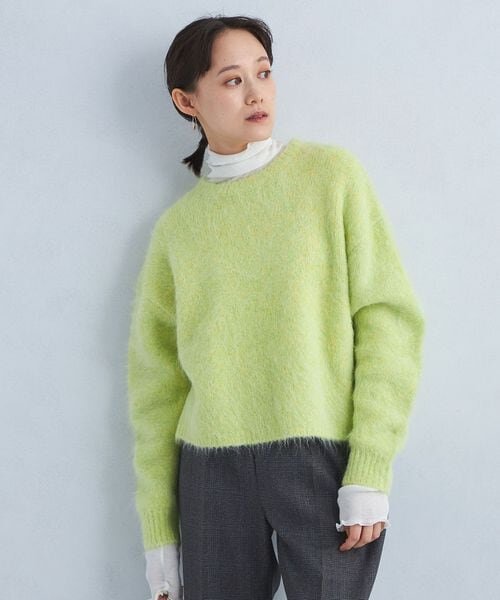 グリーンのショート丈ニットを着た女性