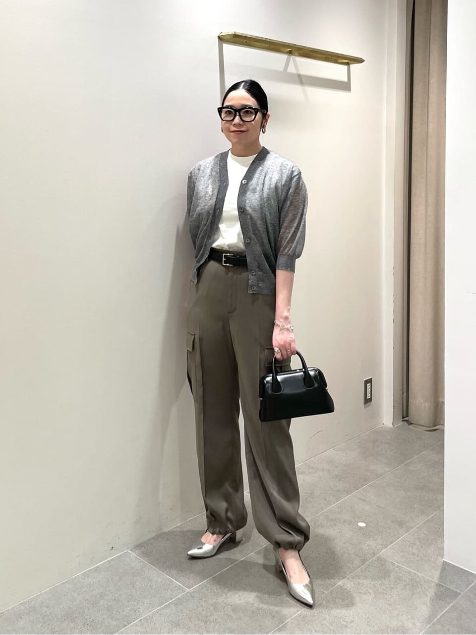 グレーのカーディガンとカーキのパンツを着た女性