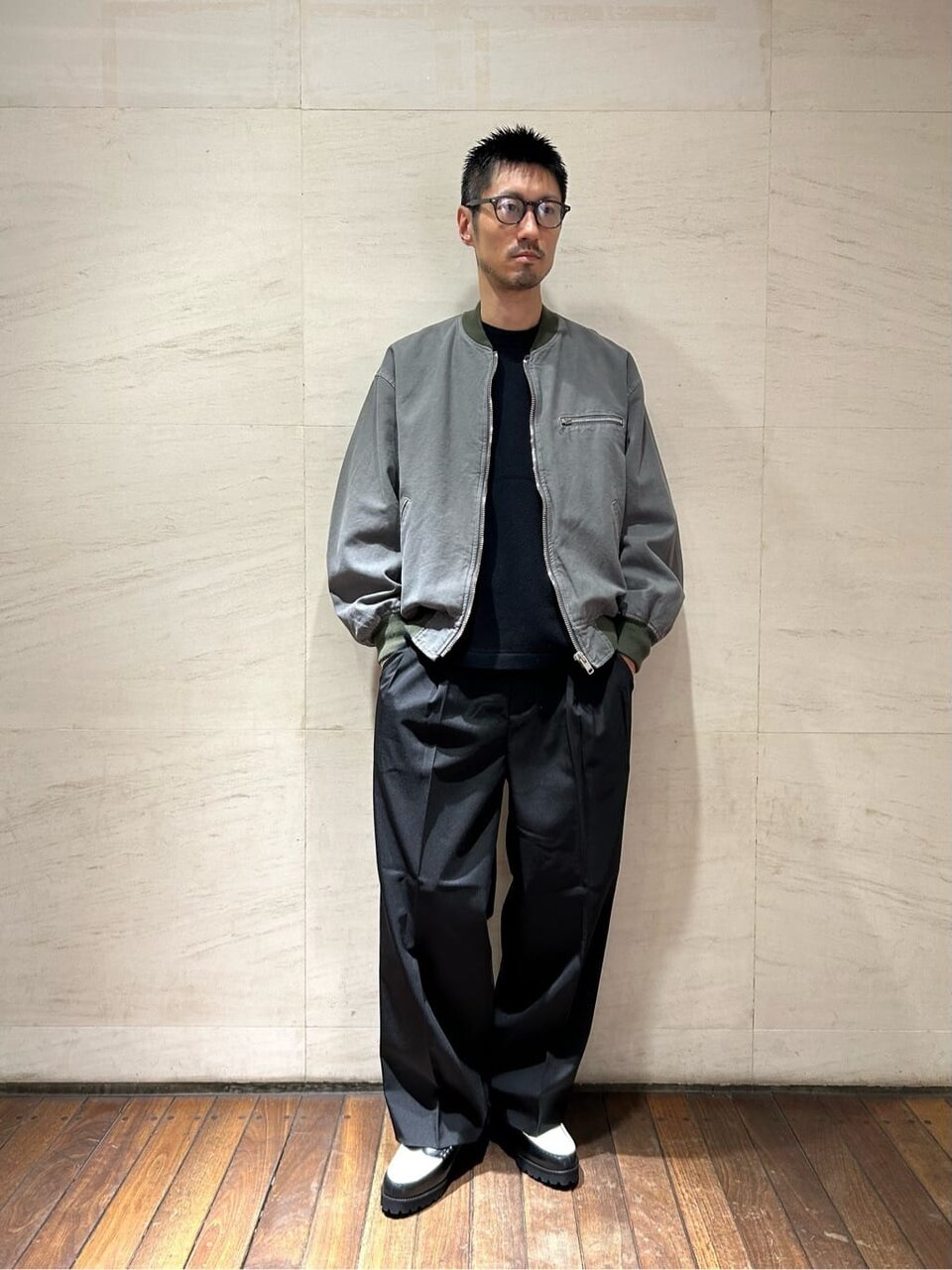 グレーのボンバージャケットとワイドパンツを着た男性