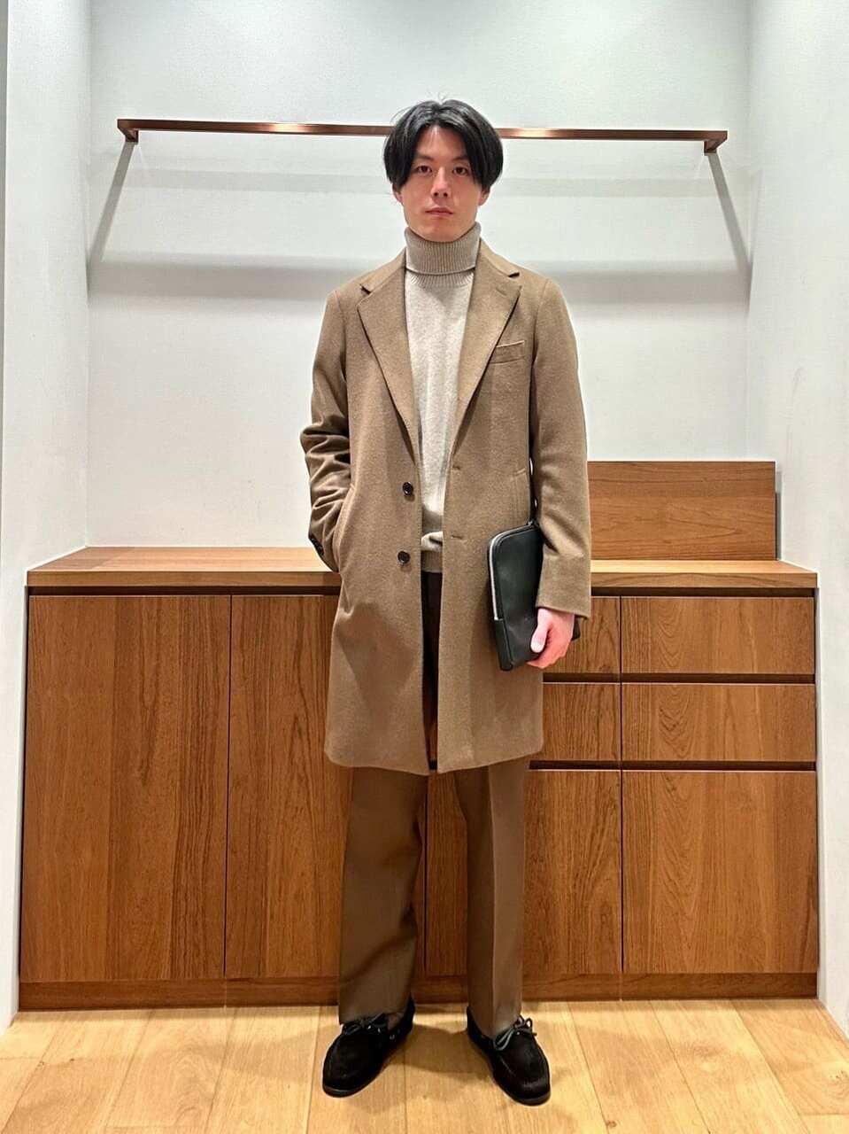 チェスターコートとブラウンのパンツを着た男性