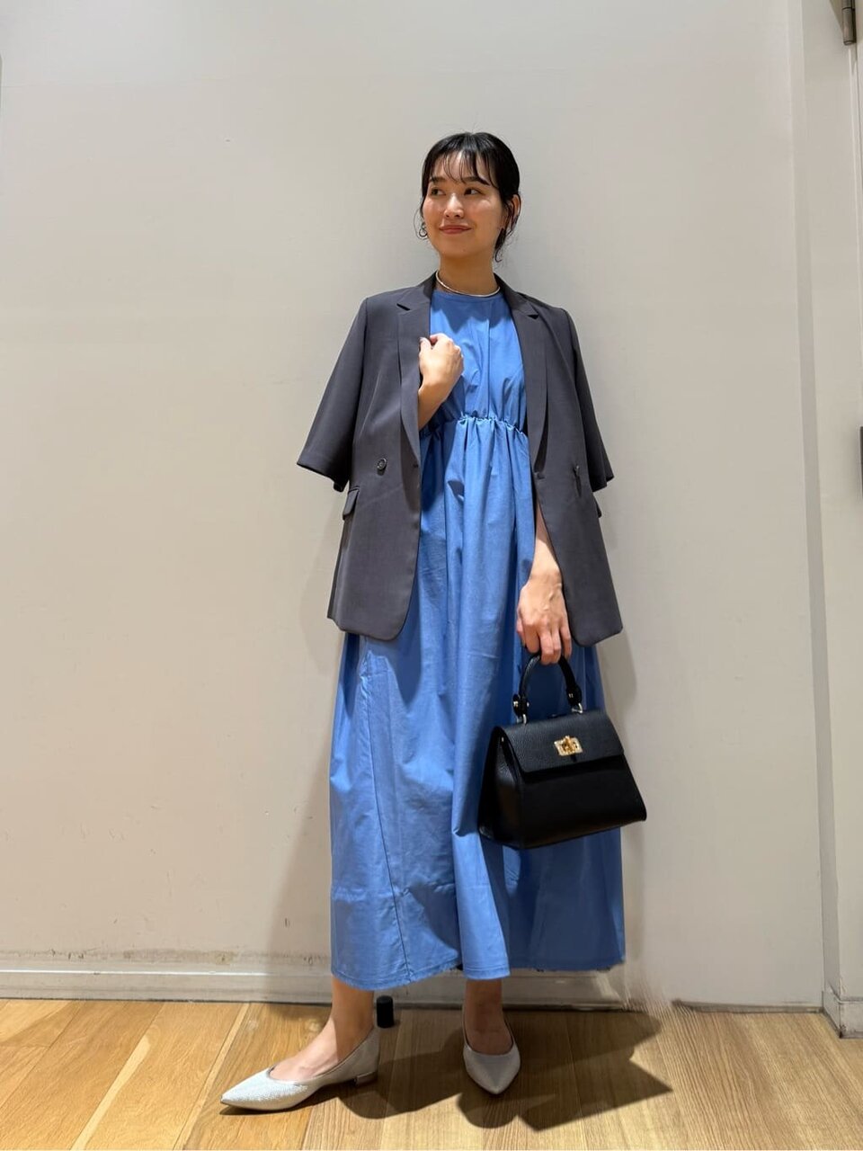 テーラードジャケットとブルーのワンピースを着た女性
