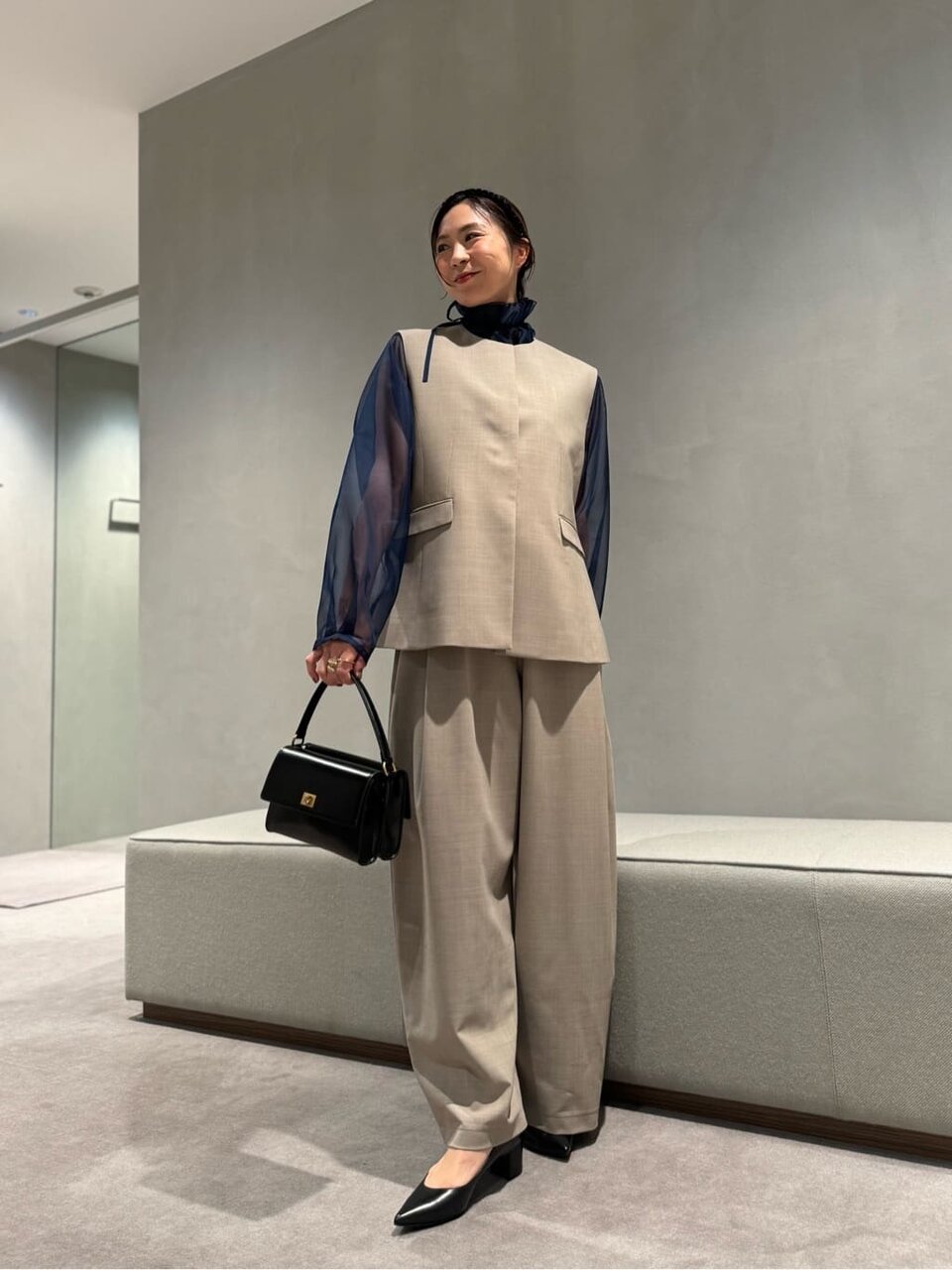 ノーカラーベストとオールインワンを着た女性