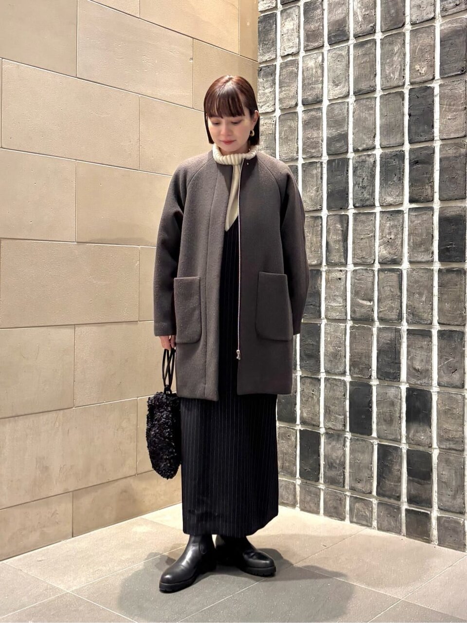 ノーカラーコートとキャミワンピースを着た女性