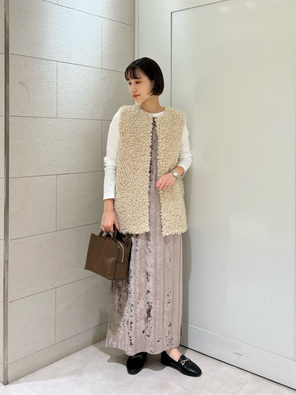 ノーカラーコートとキャミワンピースを着た女性