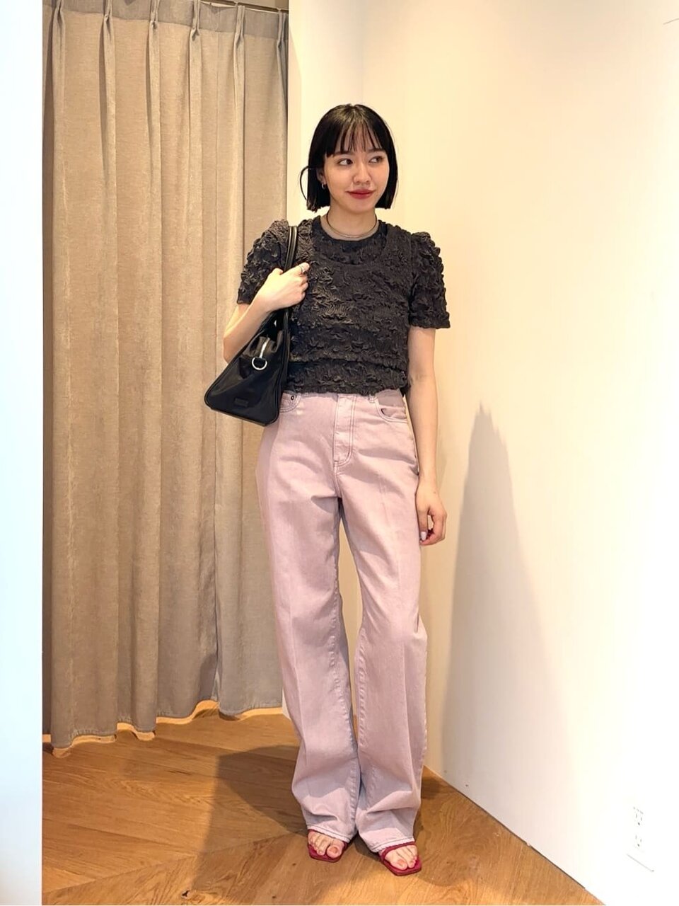 黒のシャーリングブラウスとピンクのデニムを着た女性
