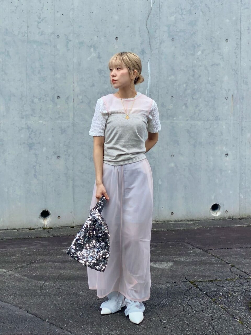 ピンクのノースリーブワンピースとシルバーのパンツを着た女性