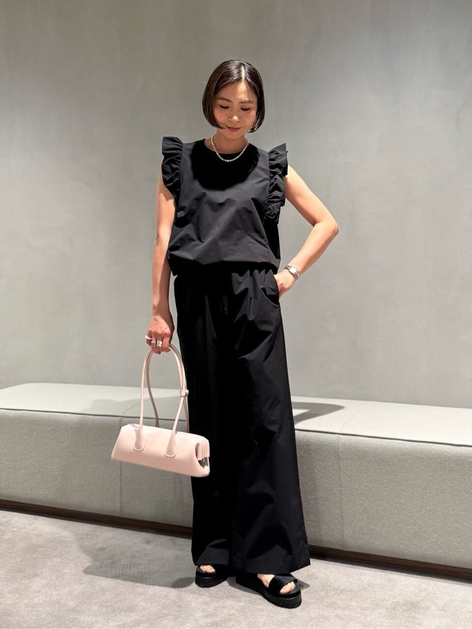 黒のオールインワンにピンクのバッグをあわせた女性