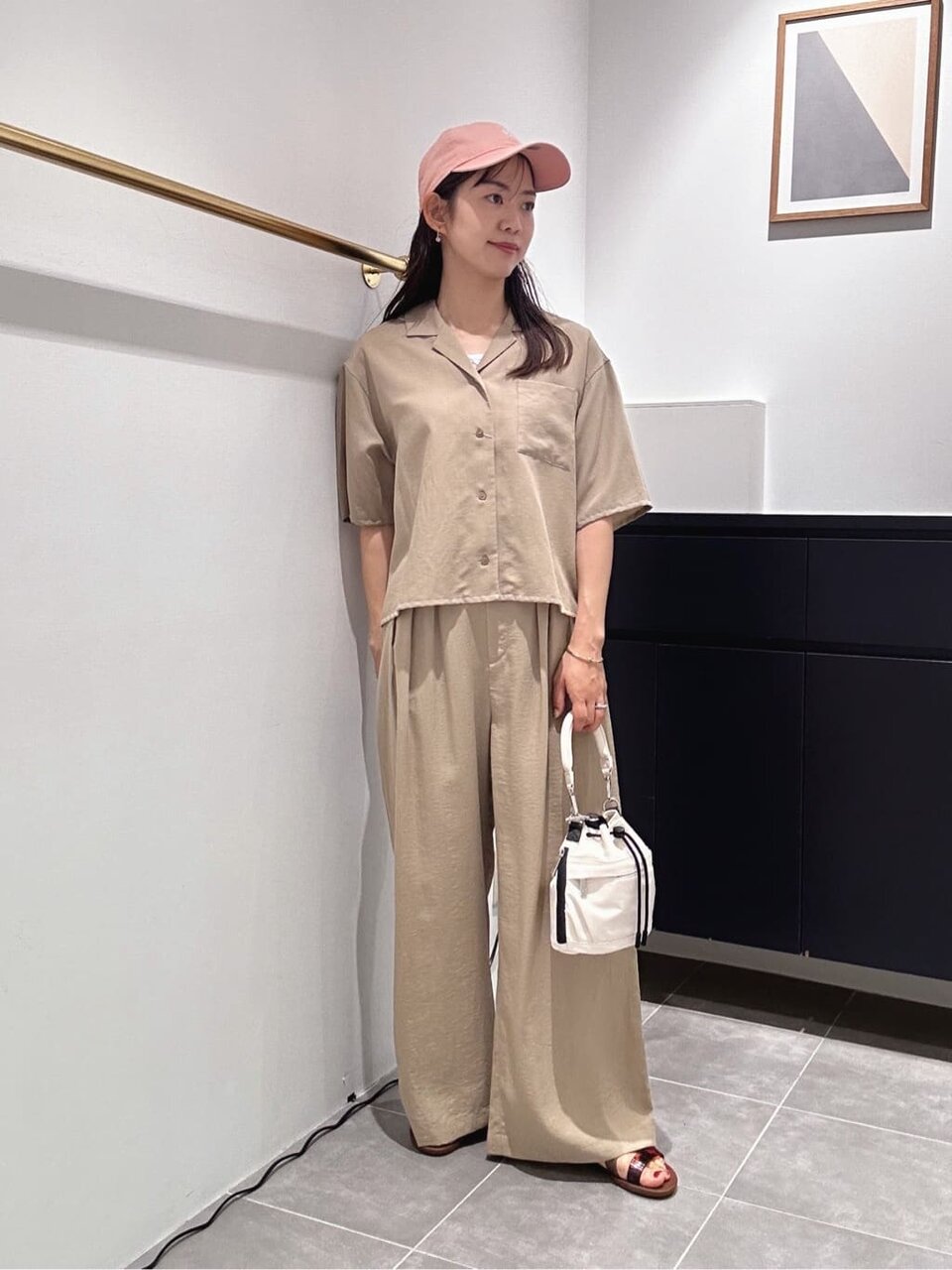 ベージュのセットアップにピンクのキャップをあわせた女性