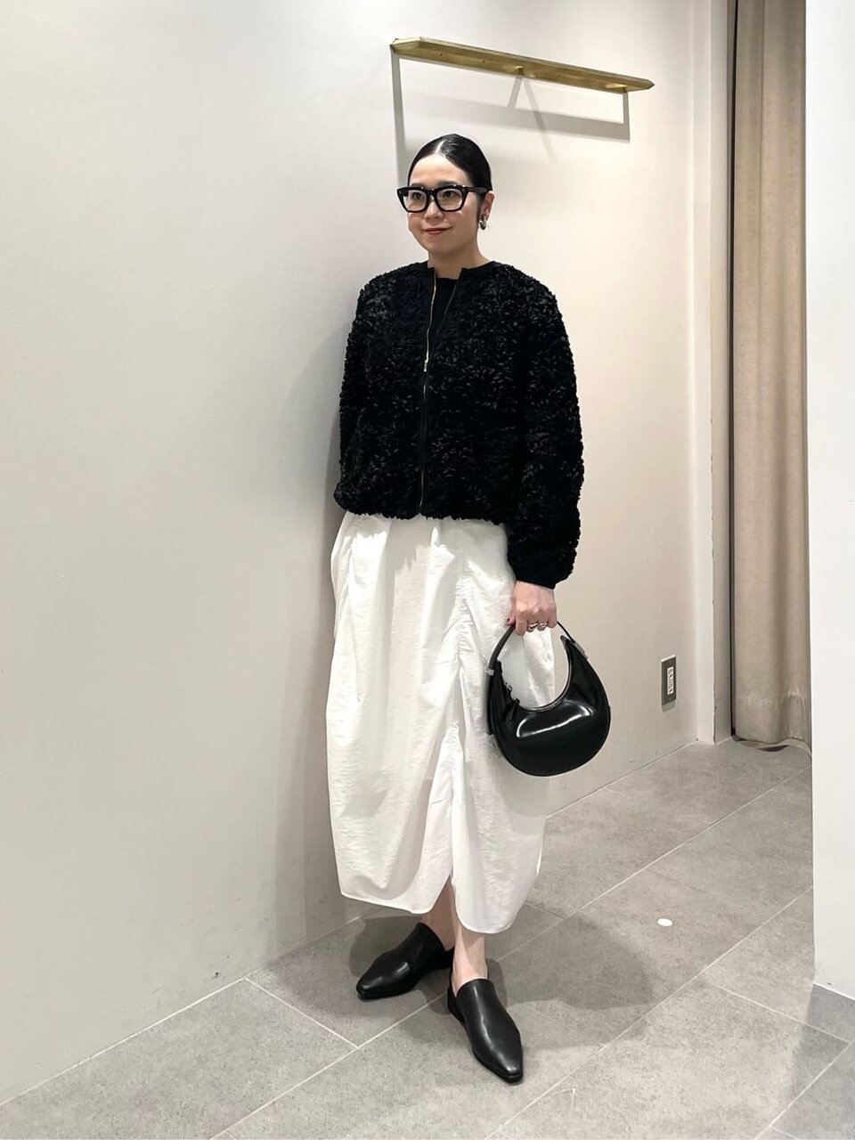 黒のブルゾンにスカートをあわせた女性