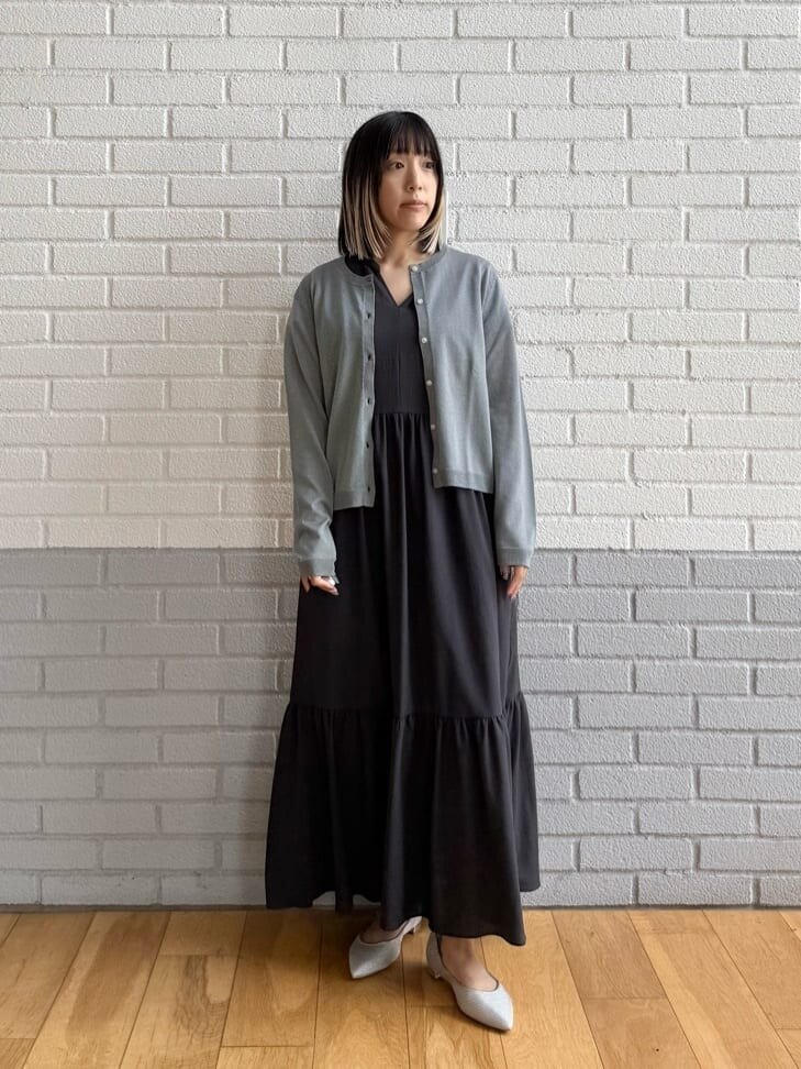 グレーのワンピースとカーディガンを着た女性
