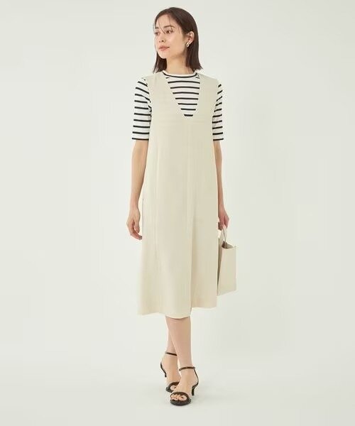 Vネックのワンピース（ジャンパースカート）を着た女性