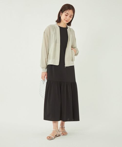 黒のワンピースにブルゾンを羽織った女性