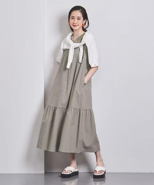 ノースリーブワンピースにカーディガンを肩掛けした女性