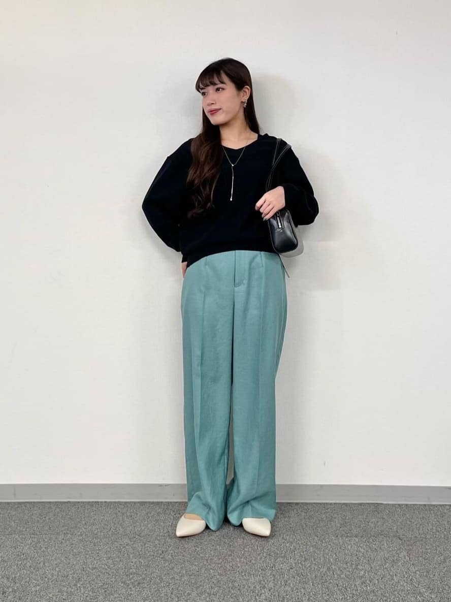 黒ニットとグリーンのパンツの女性